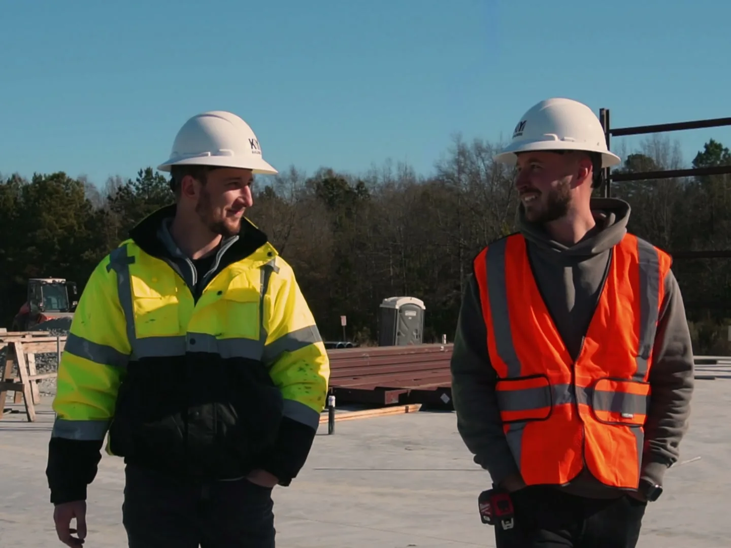 Two builders in hard hats walking across a new building floor, commercial general contractor