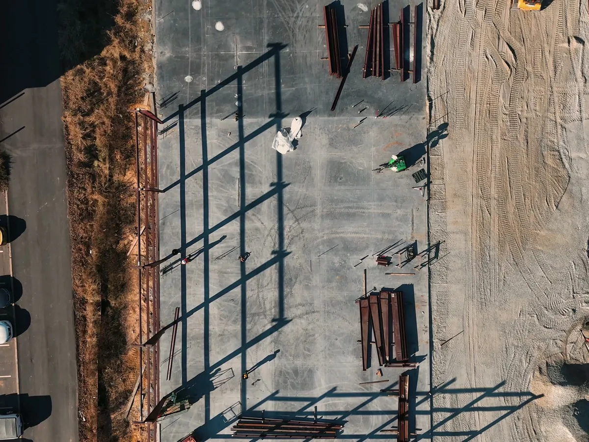Overhead view of new steel columns on a slab beside a parking lot, commercial additions