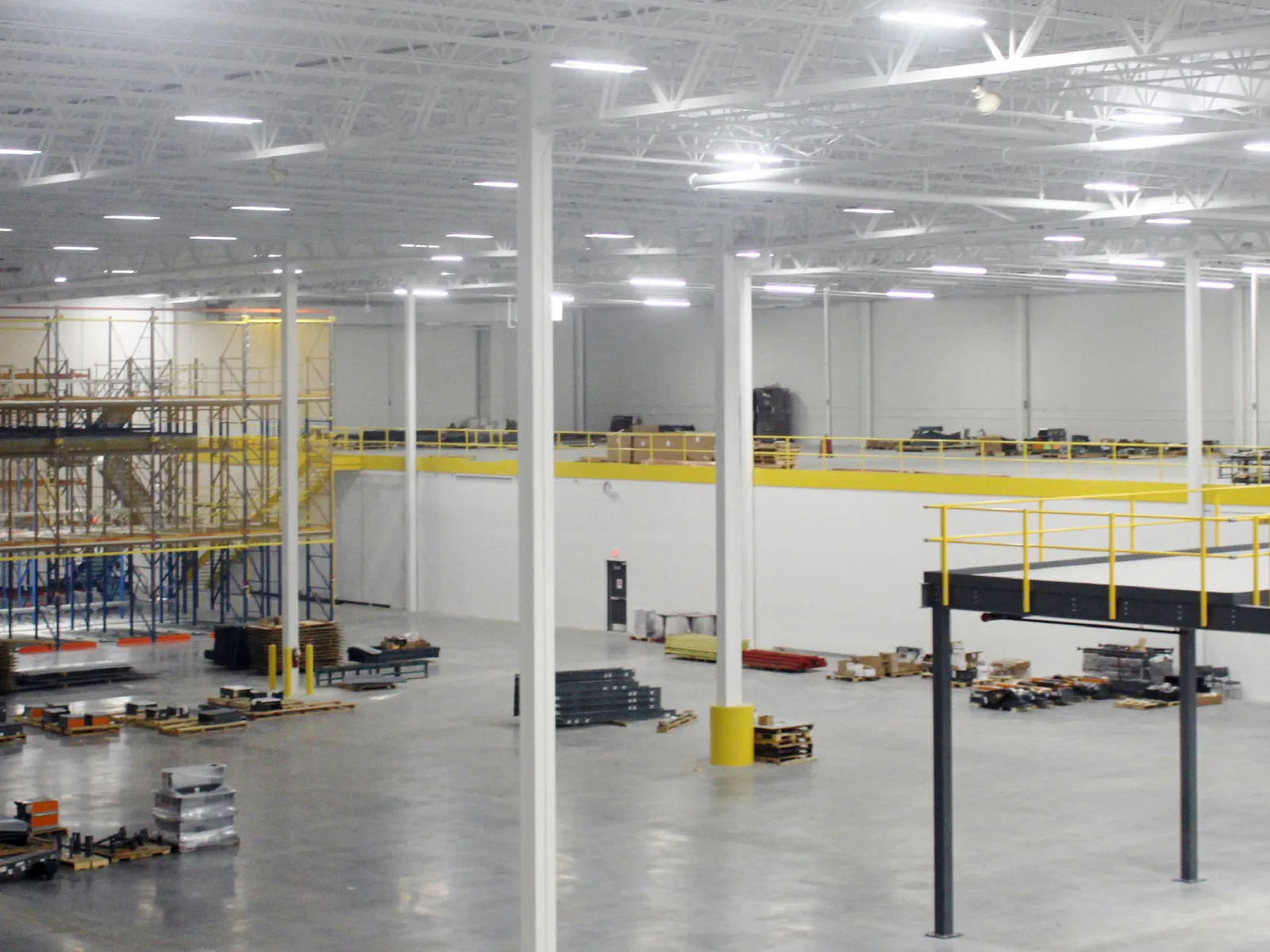 New warehouse interior with steel columns, open web roof joists and a steel mezzanine, commercial additions