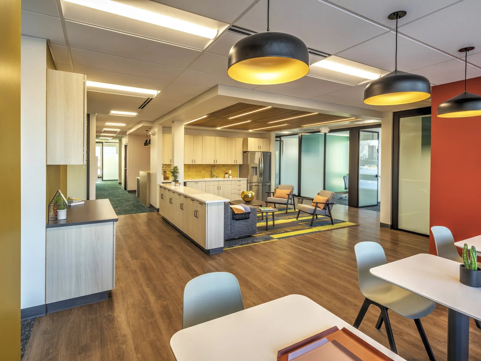 Renovated office break room with a kitchenette, lounge seating and glass front offices, commercial remodeling