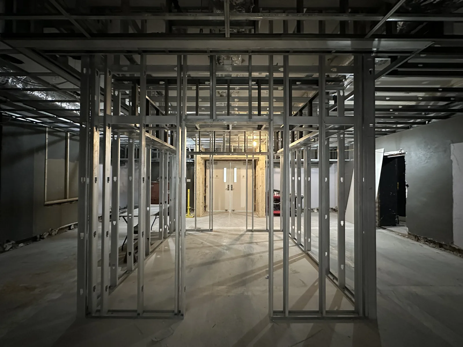 New metal stud wall framing inside a gutted building with double doors at the back, commercial remodeling