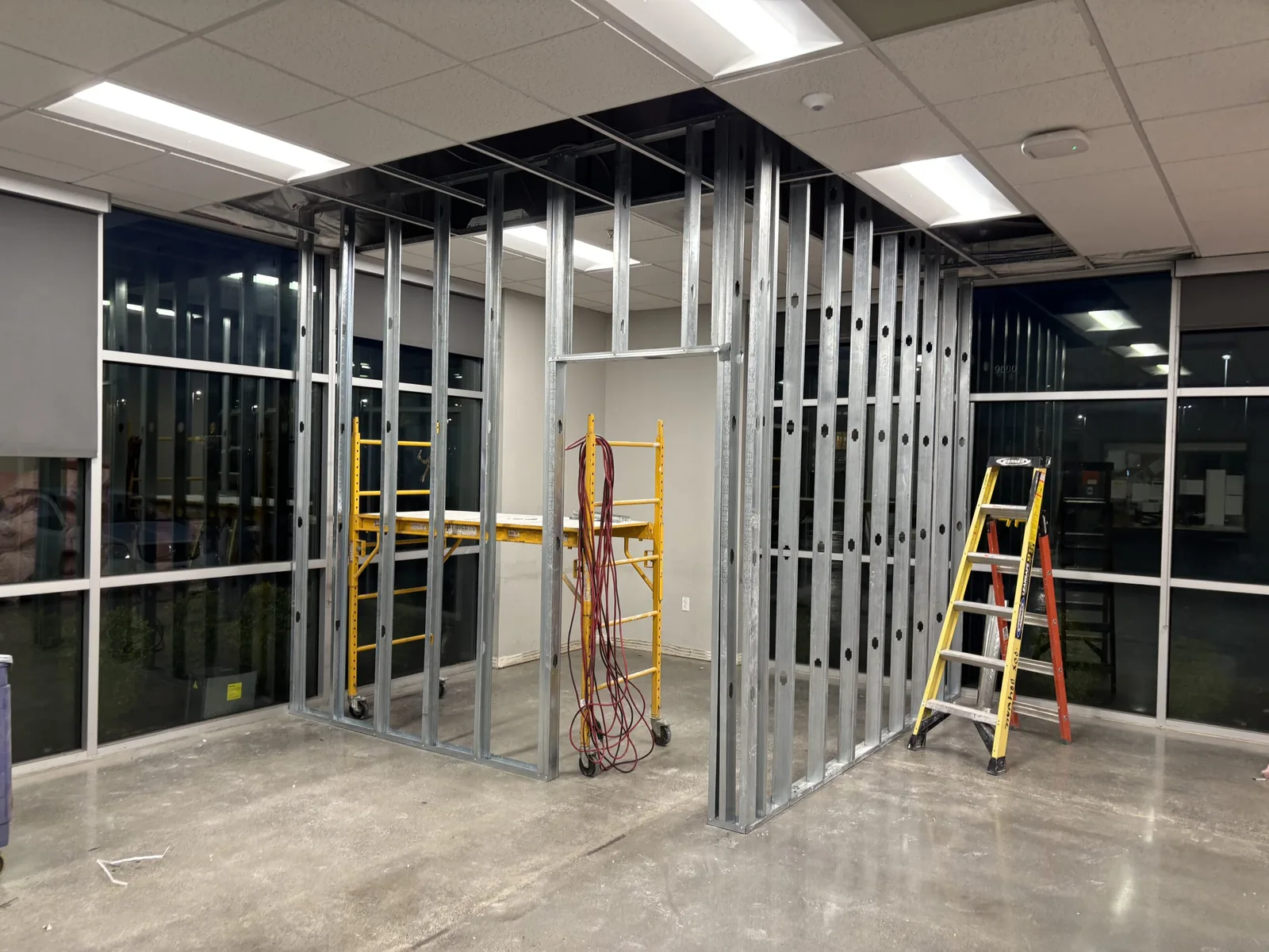 Metal stud framing for a new room inside an office space with storefront windows, commercial upfits