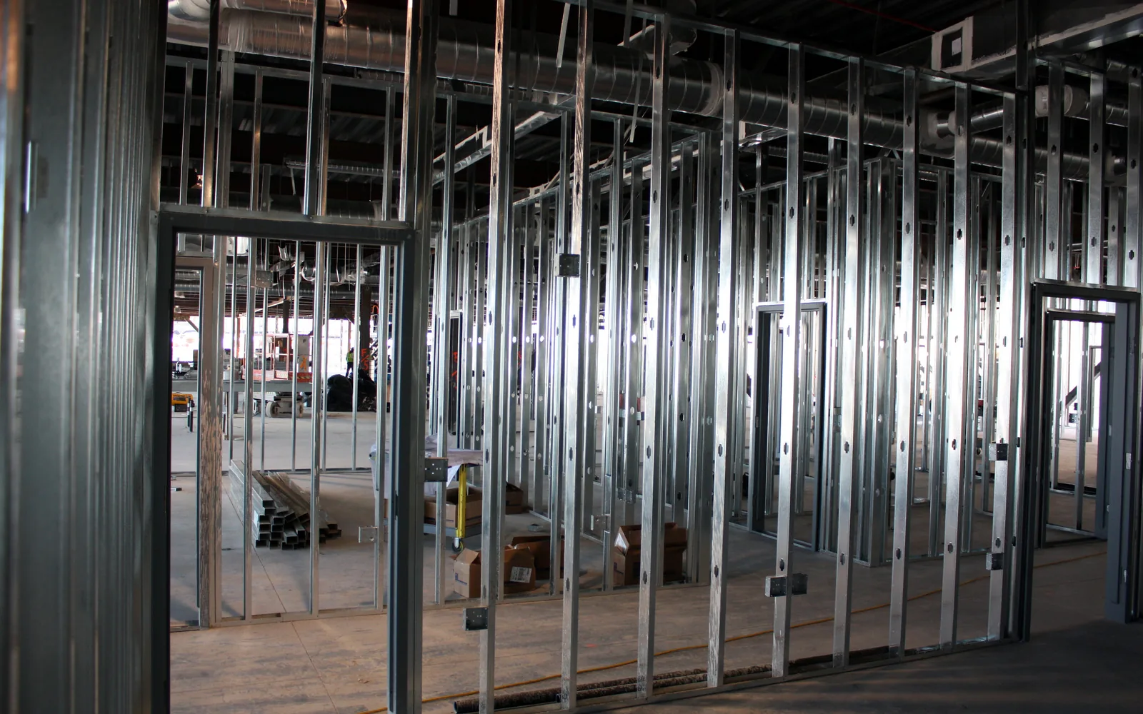 Metal stud walls and door openings framed across a large interior build out under exposed ductwork, commercial upfits