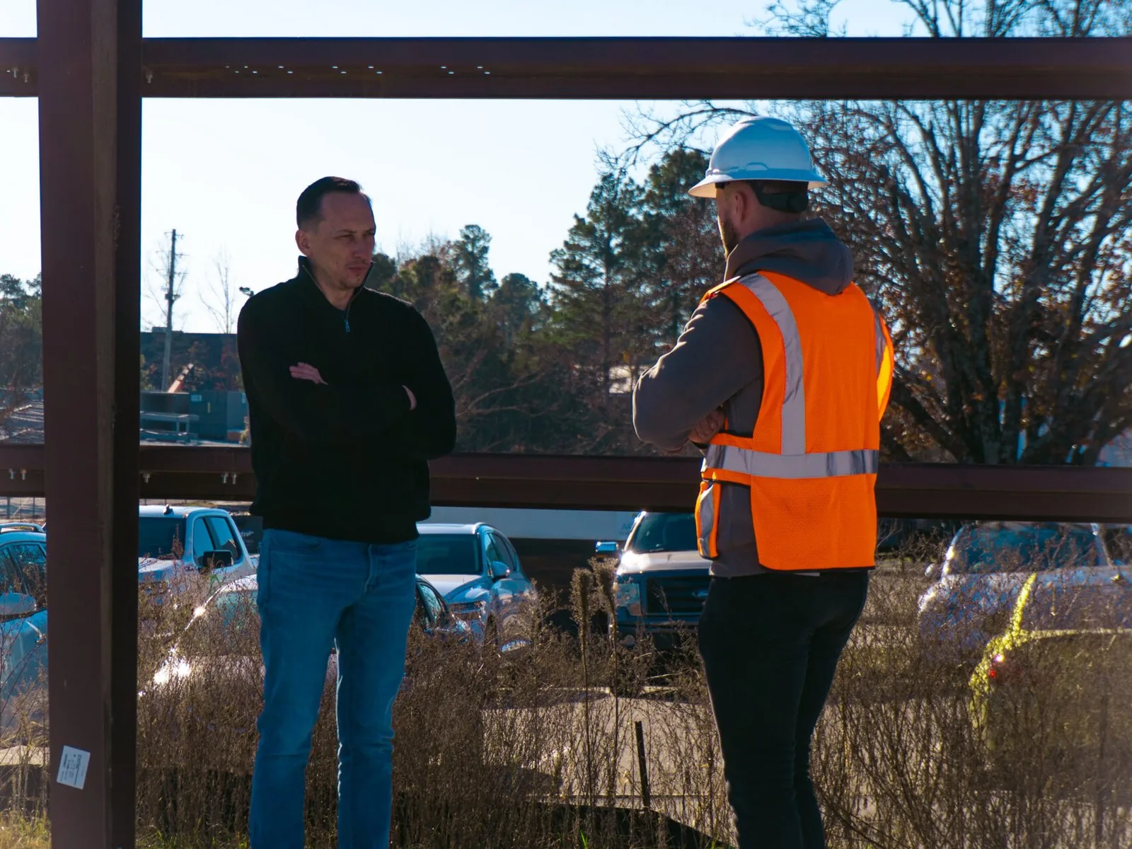 Two builders talking beside a steel column on a commercial job site, design build