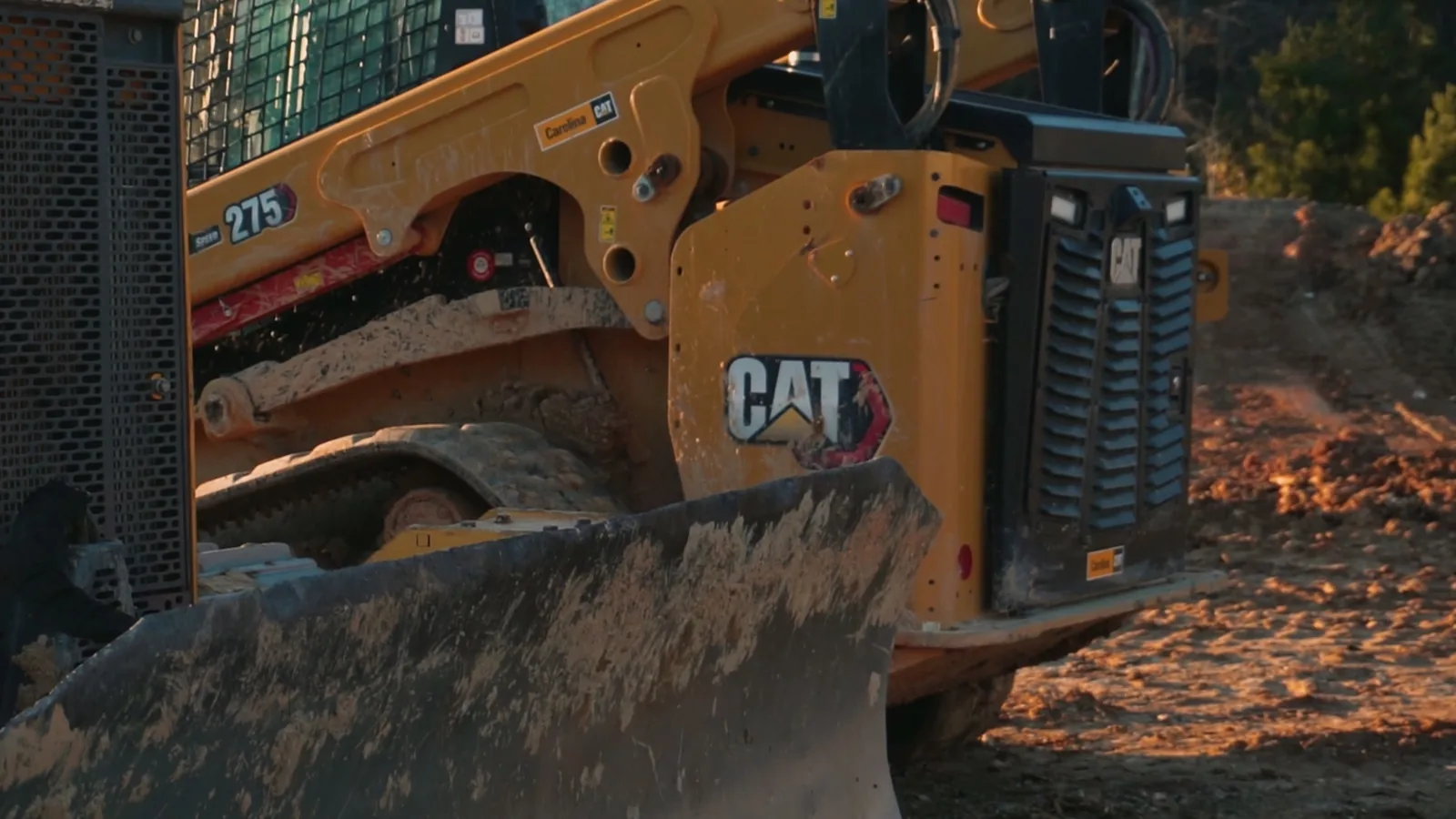 Compact track loader with a dozer blade on a red clay job site, commercial general contractor