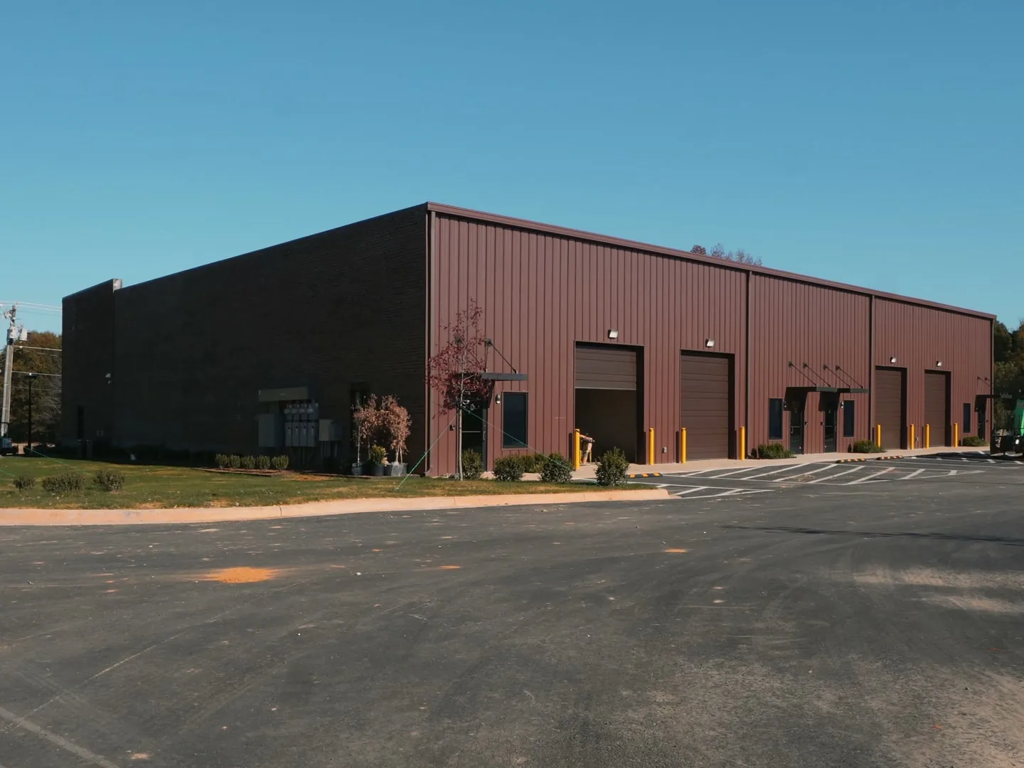 Finished metal flex building with overhead doors facing a new asphalt lot, flex space construction