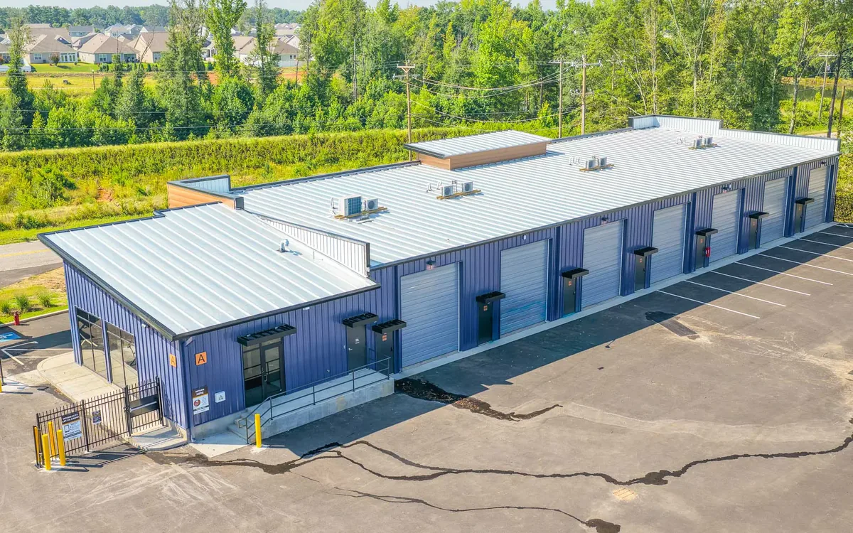 Aerial view of a finished blue metal flex building with a glass office entry, roll up doors and a new parking lot, flex space construction