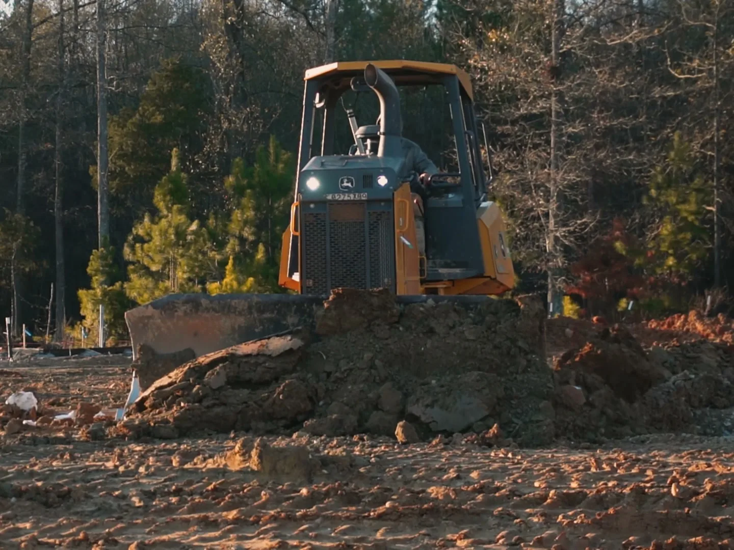 Dozer pushing dirt while clearing a wooded commercial site, ground up construction