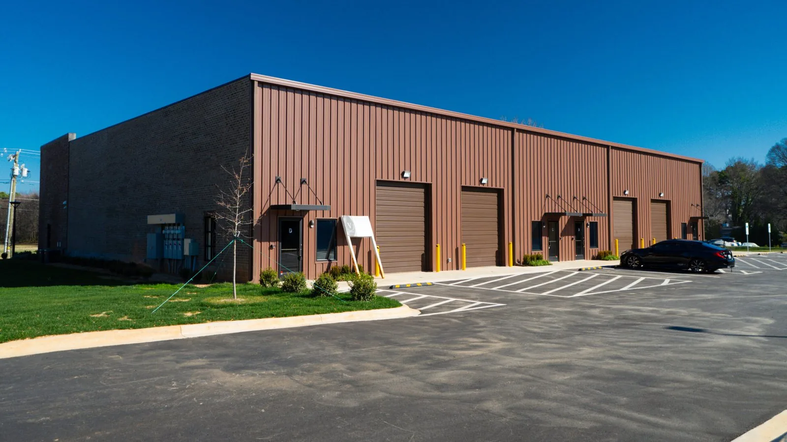 Finished dark red metal flex building with roll up doors and a new parking lot, commercial general contractor