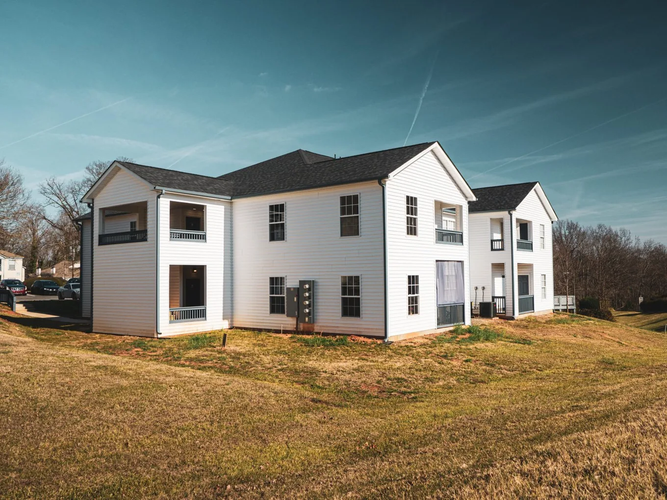 Rear of a two story multi family building with covered porches and a bank of electric meters, multi family construction