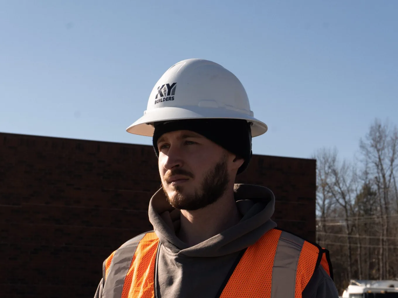 Builder in a hard hat and safety vest looking across a commercial job site, preconstruction