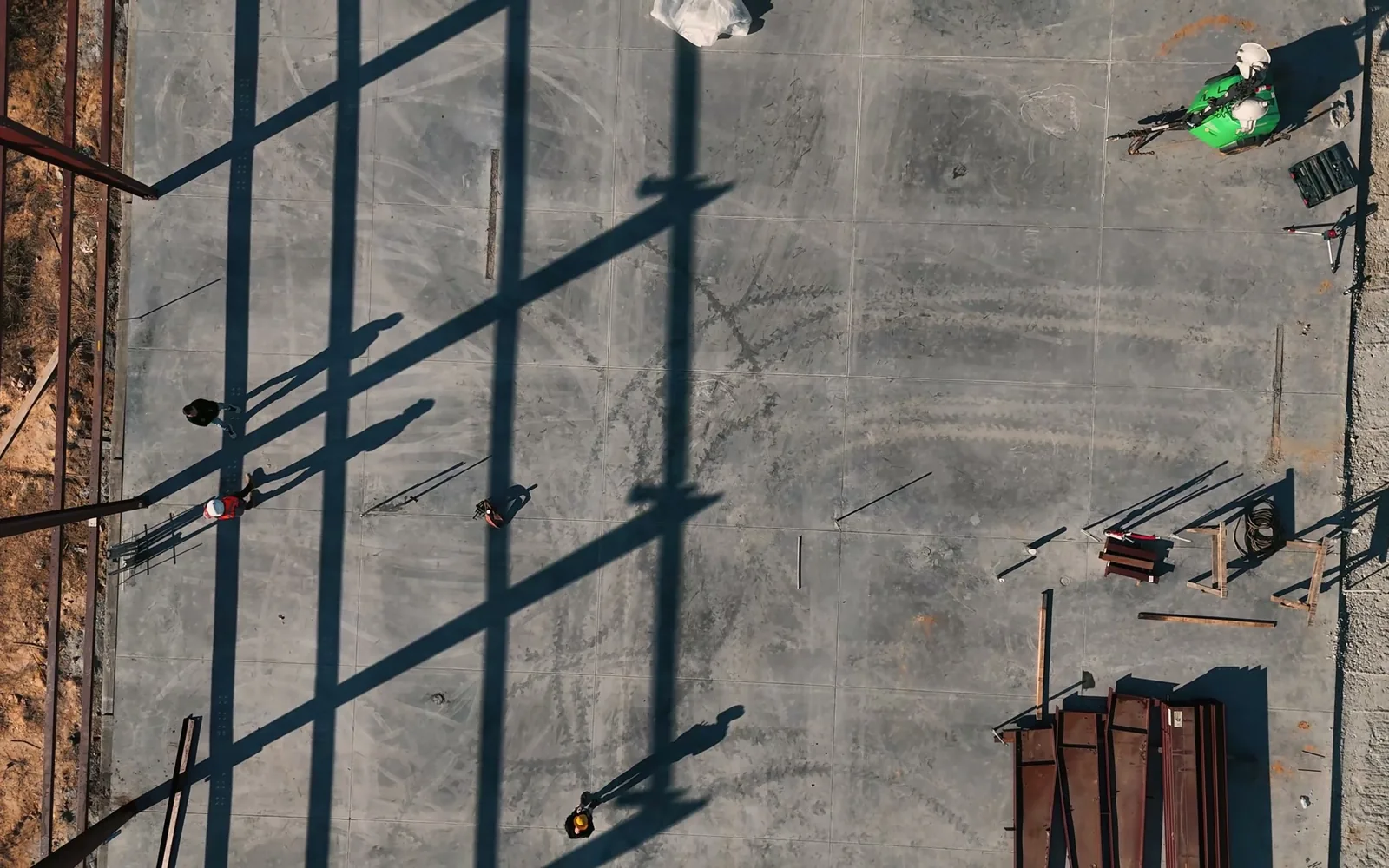 Overhead view of steel columns casting long shadows across a new slab, warehouse construction