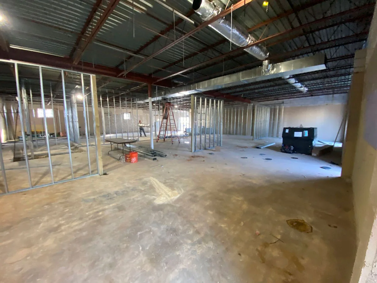 Metal stud walls going up inside an existing steel joist warehouse with ductwork overhead, warehouse renovation